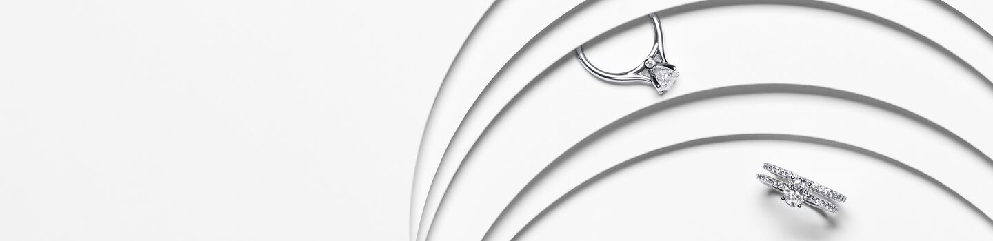 Birks 1879 and Birks Ros&eacute;e du Matin diamond solitaire engagement rings on a white layered background.